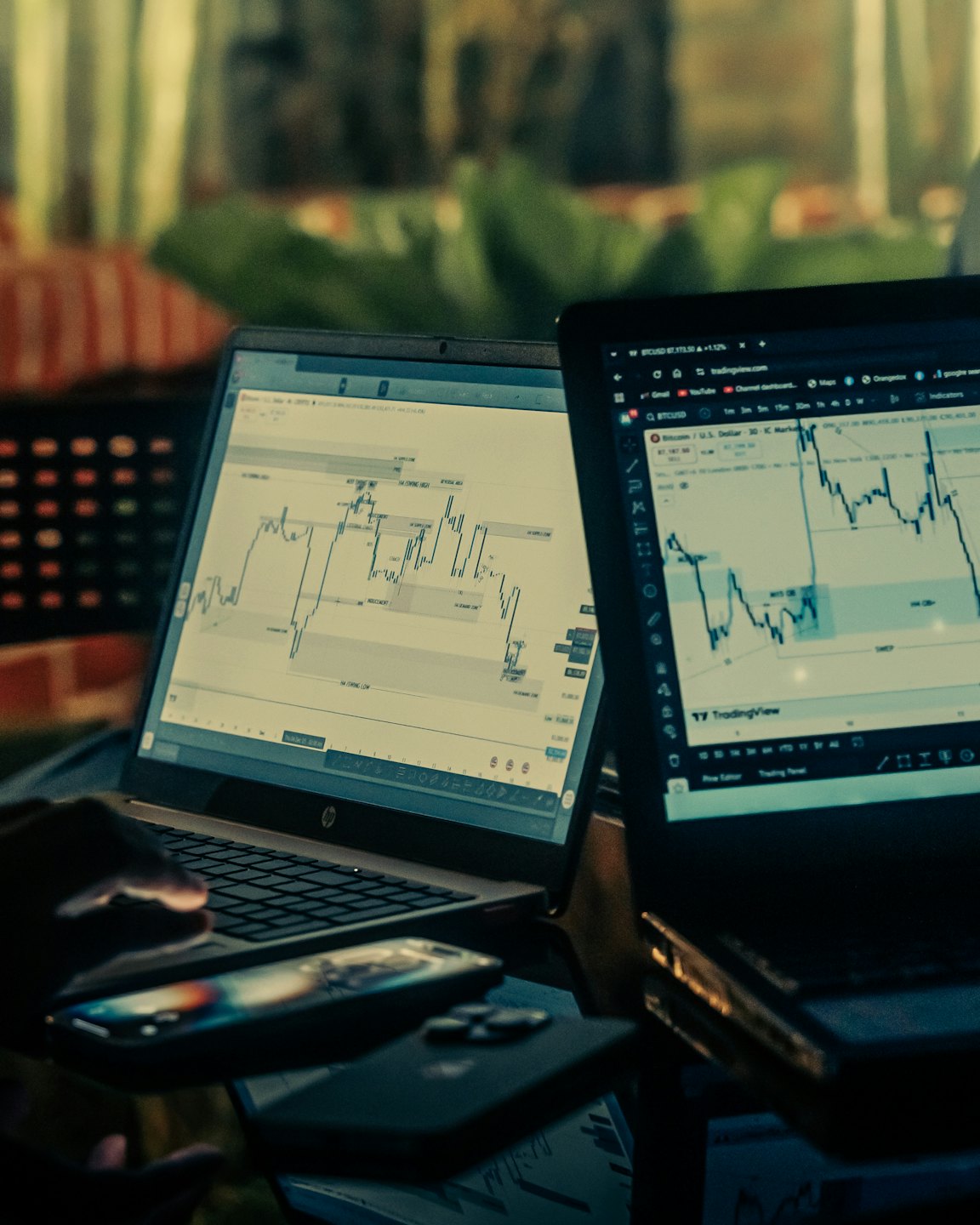 Person types on a laptop while monitoring multiple financial trading charts.